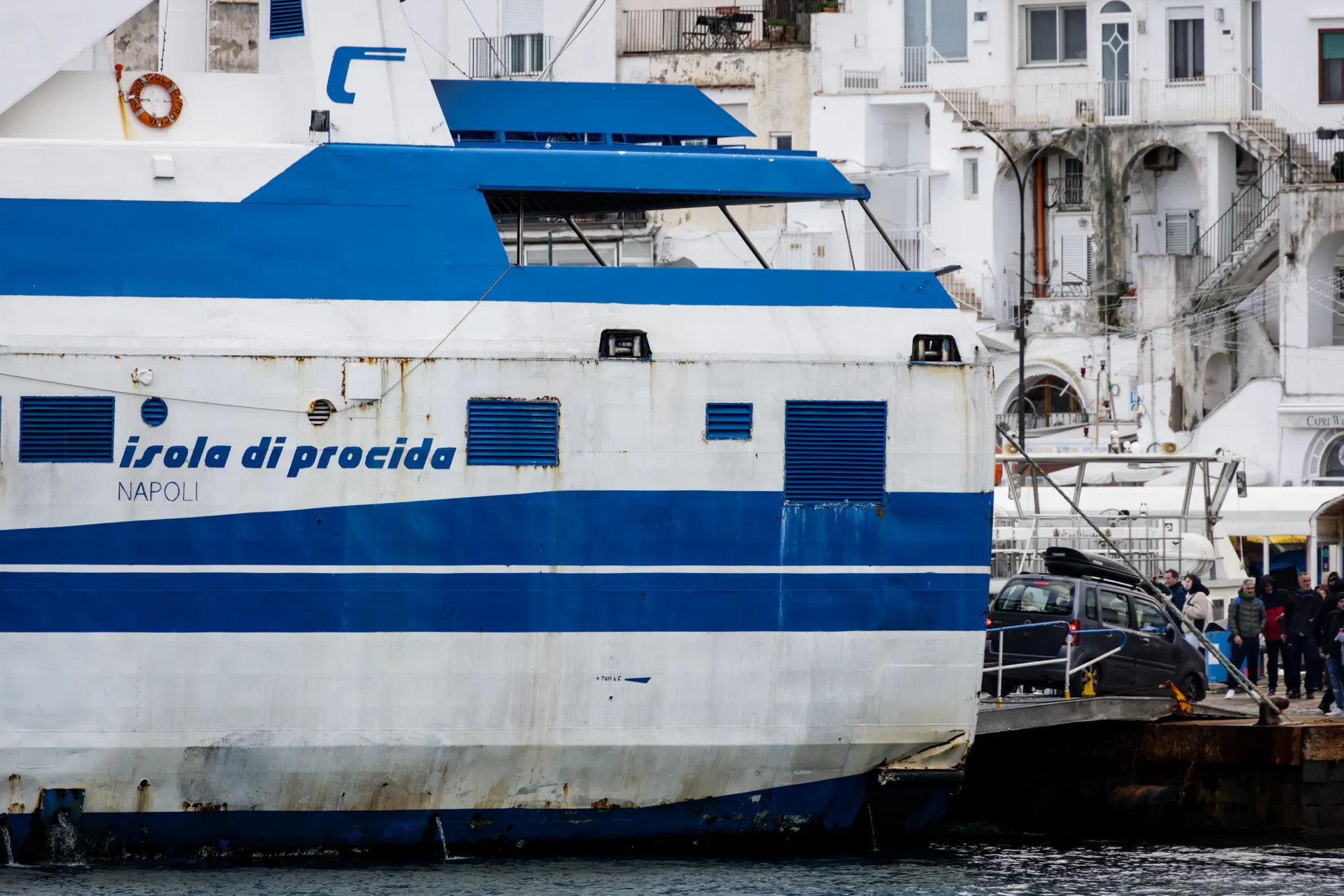 View of Isola di Procida ferry at a port in Naples, Italy with Mediterranean architecture.
